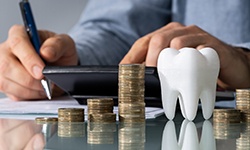 A model tooth in front of a businessperson calculating a bill