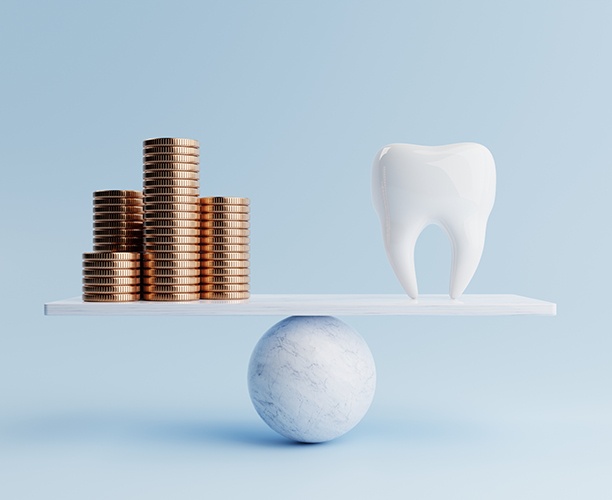 A balance beam holding a large tooth and stacks of coins