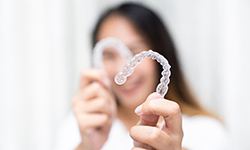 Smiling patient holding up clear aligners