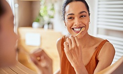 Woman smiling while brushing her teeth