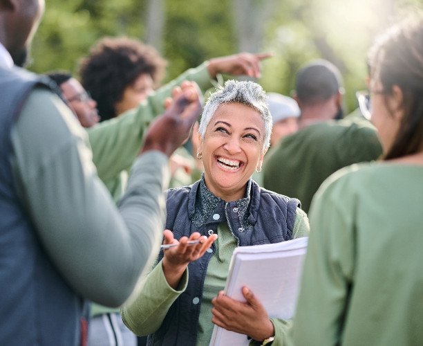 Woman smiling while talking to group of people outside