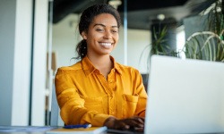 Woman smiling while working on laptop in office