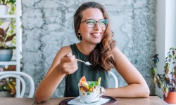 Woman smiling while eating healthy breakfast at home