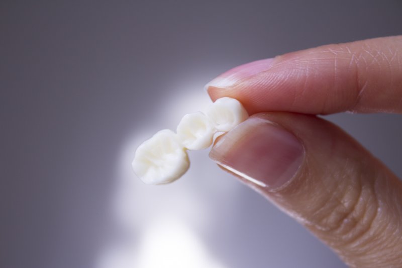 A dental bridge held between two fingers